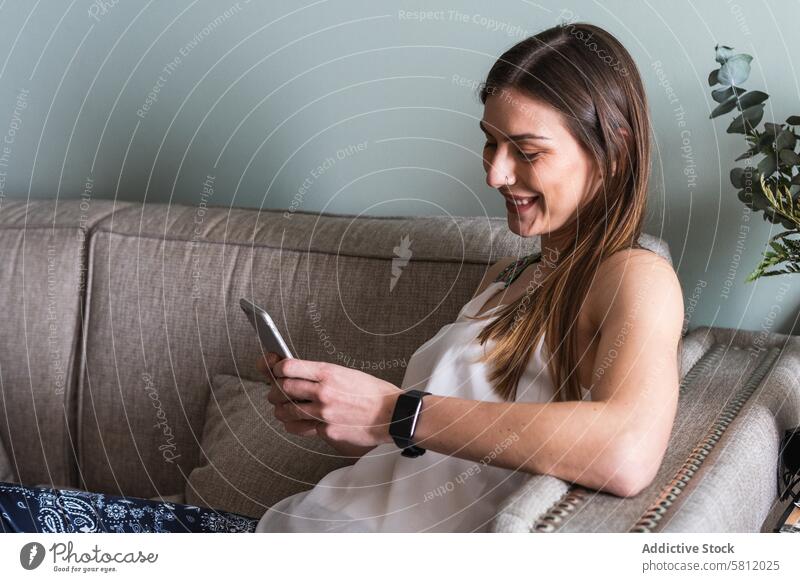 Woman chatting on smartphone on sofa at home woman spare time weekend internet legs crossed house using gadget device lifestyle cellphone text messaging