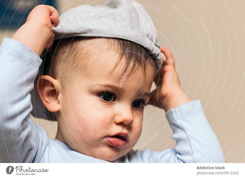 cute baby putting on a hat at home child childhood kid little happy small white innocence adorable cheerful beautiful caucasian portrait healthy young toddler