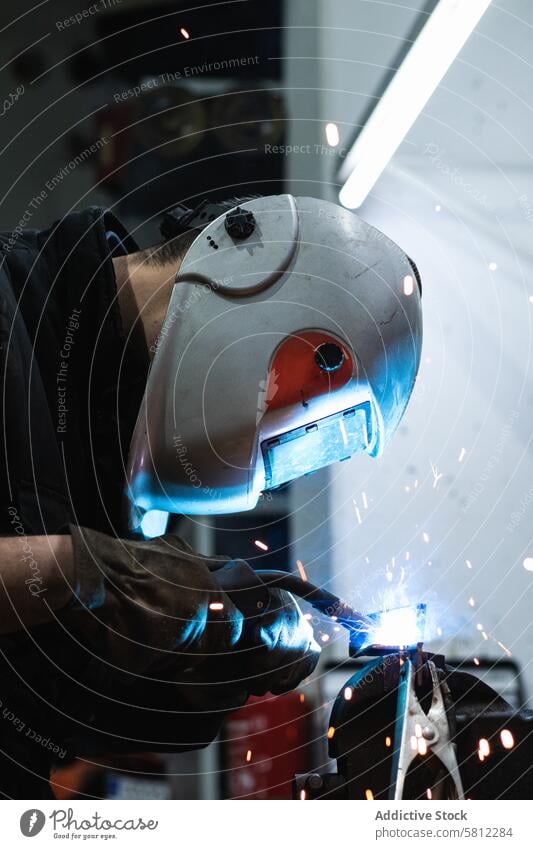 Anonymous mechanic welding metal construction in workshop man garage torch spark job repairman safety labor protect male equipment occupation helmet metalwork