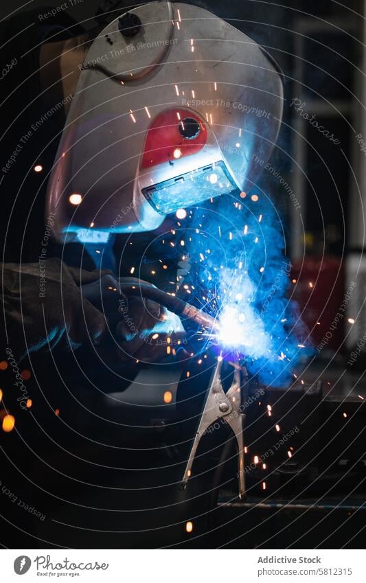 Anonymous mechanic welding metal construction in workshop man garage torch spark job repairman safety labor protect male equipment occupation helmet metalwork