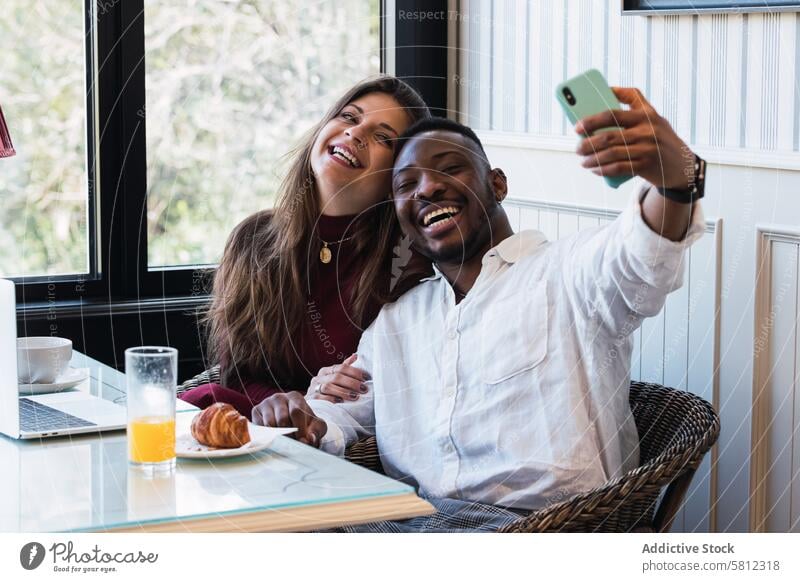 Cheerful multiethnic couple using laptop at home while taking a selfie together happy cheerful browsing relationship love multiracial diverse black smile