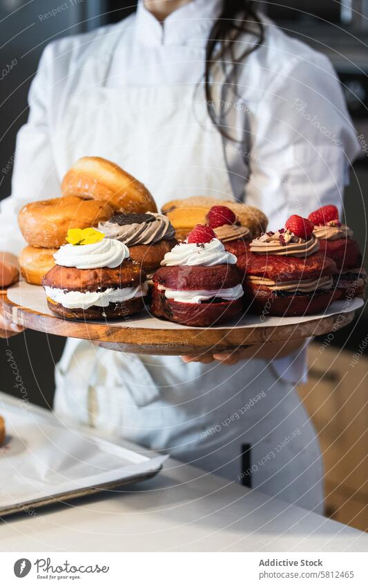 Crop woman with Berliners on tray in bakery vegan berliner dessert bakehouse tasty assorted female cuisine culinary yummy gourmet uniform fresh food delicious