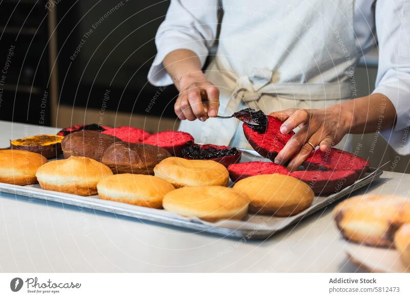 Crop cook adding jam on sponge cakes in bakehouse baker spread vegan dessert smear kitchen bakery chef cuisine culinary pastry sweet food delicious gastronomy