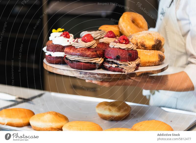 Crop woman with Berliners on tray in bakery vegan berliner dessert bakehouse tasty assorted female cuisine culinary yummy gourmet uniform fresh food delicious