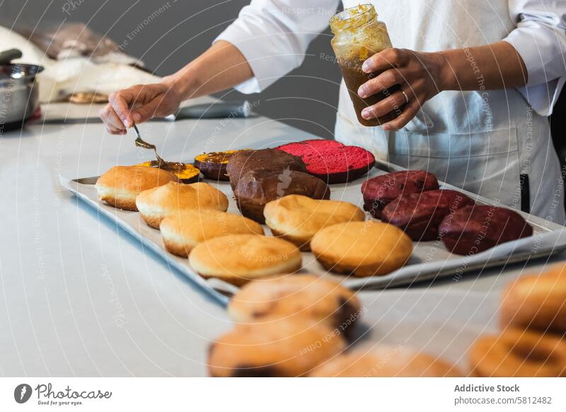 Crop cook adding jam on sponge cakes in bakehouse baker spread vegan dessert smear kitchen bakery chef cuisine culinary pastry sweet food delicious gastronomy