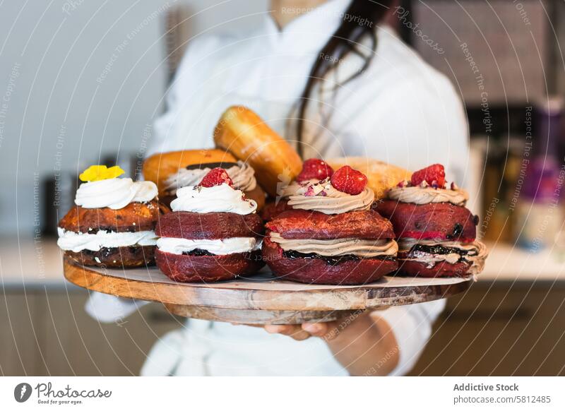 Crop woman with Berliners on tray in bakery vegan berliner dessert bakehouse tasty assorted female cuisine culinary yummy gourmet uniform fresh food delicious