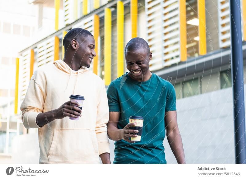 Happy best black friends laughing with takeaway coffee on street best friend to go spare time weekend friendship interact men town disposable glass plastic