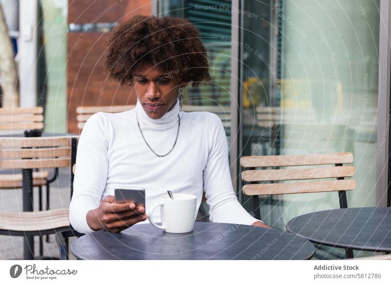 Serious young ethnic guy using smartphone in street cafe man message coffee break self esteem communicate online chill social media style internet male