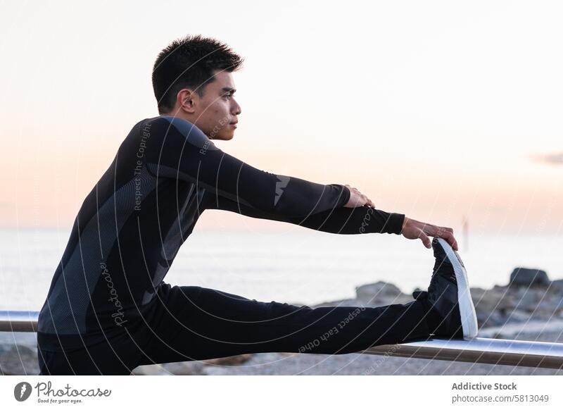 Ethnic man stretching legs during outdoor workout fitness training exercise sporty warm up sunset asian ethnic male sportsman lifestyle athlete wellness young