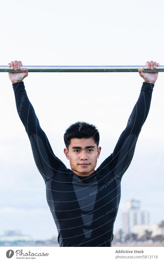 Ethnic sportsman exercising on monkey bars exercise training workout athlete activity fitness determine gymnast young asian ethnic gymnastic physical lifestyle