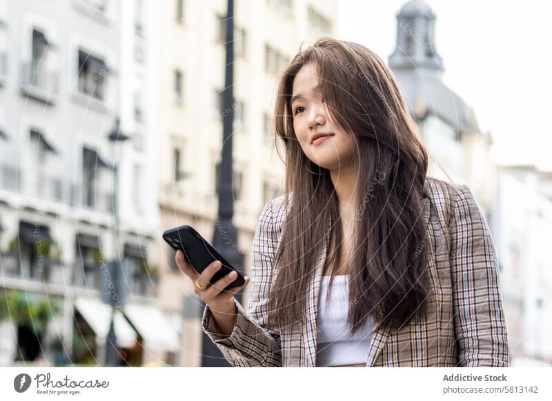 Young Asian Woman Walking and Using Smartphone in the City asian people street city young happy lifestyle walking fun outdoors women urban female cheerful