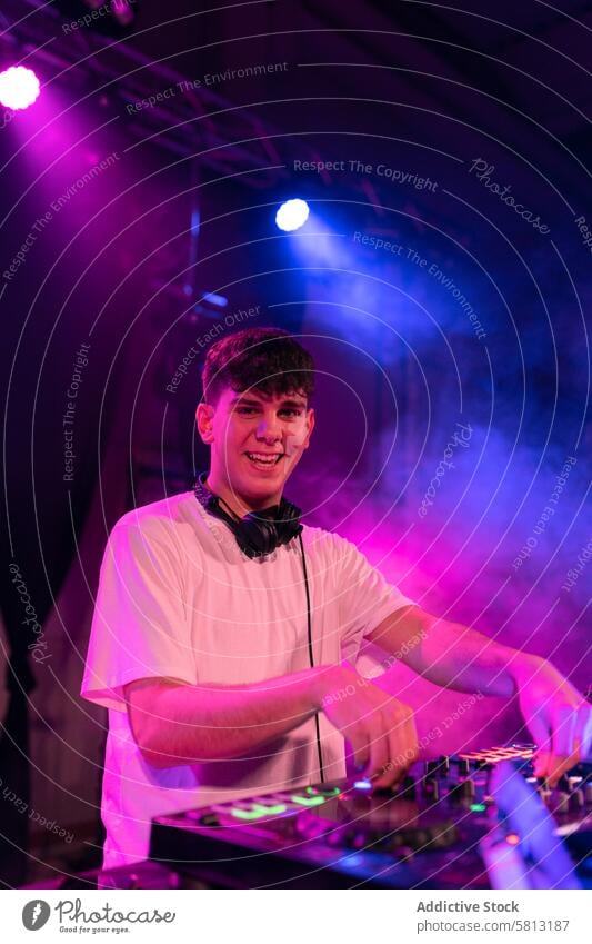 Portrait of a happy DJ smiling at camera while working vertical portrait man dj young caucasian stage nightclub disco smile looking at camera men arts