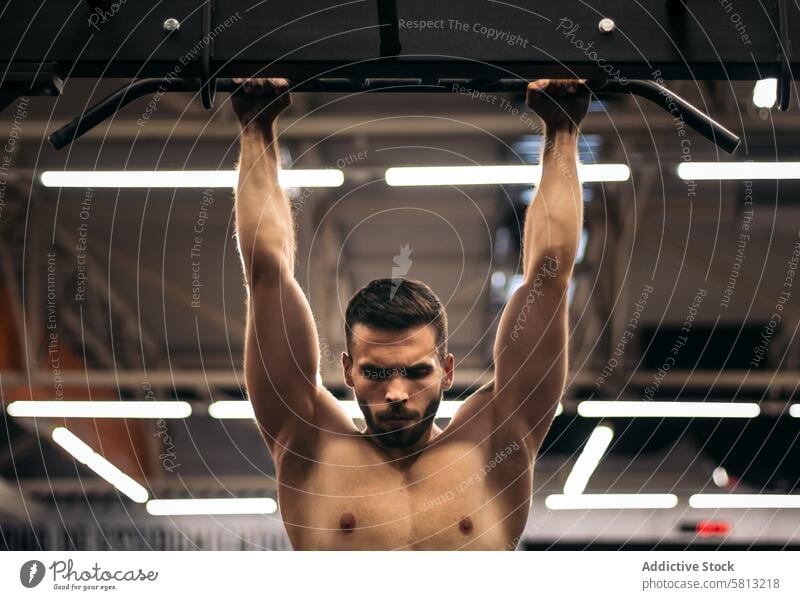 front view of a strong man doing pull ups in a gym athlete workout bar fitness training exercise male sport strength health body lifestyle physical active