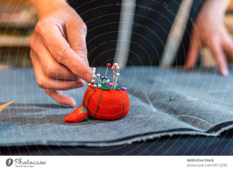 Fashion designer putting pins into a pincushion Close-up clothing confidence confident copy space copy-space craft creativity desk dressmaker equipment fabric