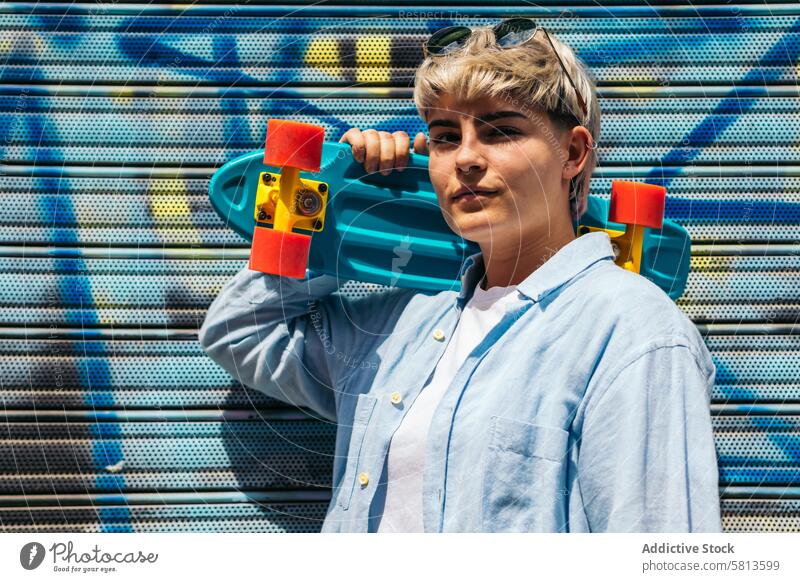 teenager girl with a skate and short hair looking at camera smiling hair wicks friendship woman young female beautiful cheerful copy space background graffiti