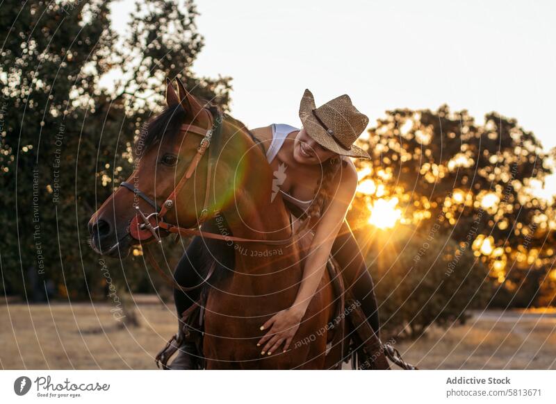 Young woman in hat riding a horse in the countryside at sunset nature young animal ranch cowgirl cowboy person equine beautiful equestrian pet female field