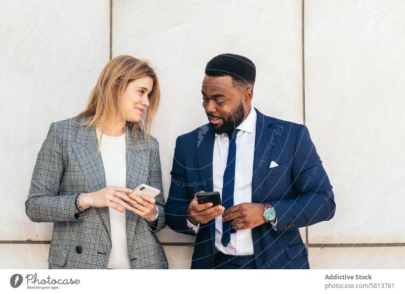 Business people and coworkers talking and using smartphone outside. They wear suits and relax on a break outside the office business meeting team professional