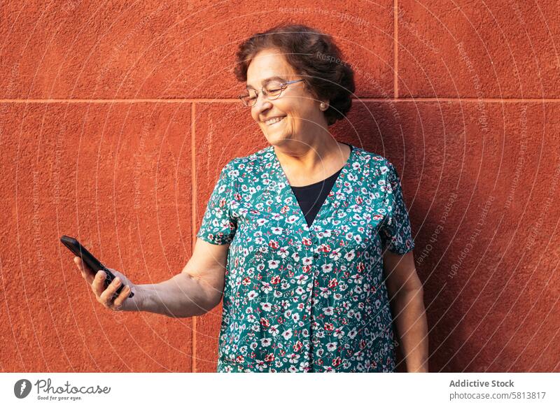 Smiling old woman using smartphone outdoors stylish mobile cellphone senior female communication device message lifestyle internet mobile phone people