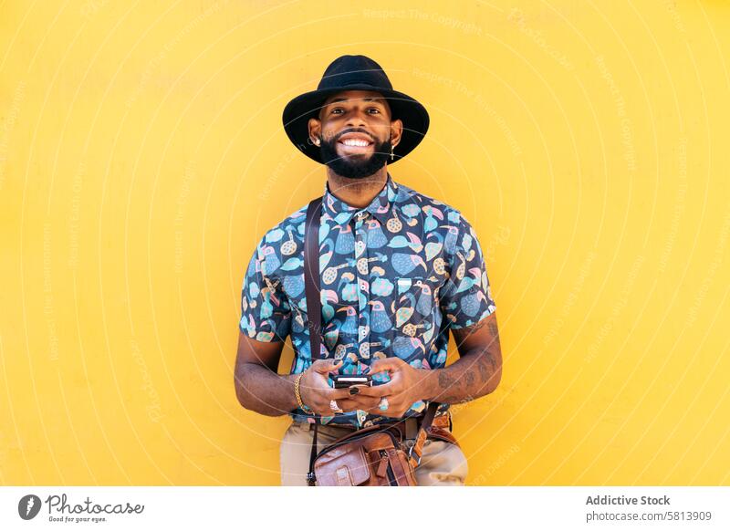 Stylish black man using smartphone outdoors over yellow background technology lifestyle city young street urban mobile male person cellphone stylish guy outside