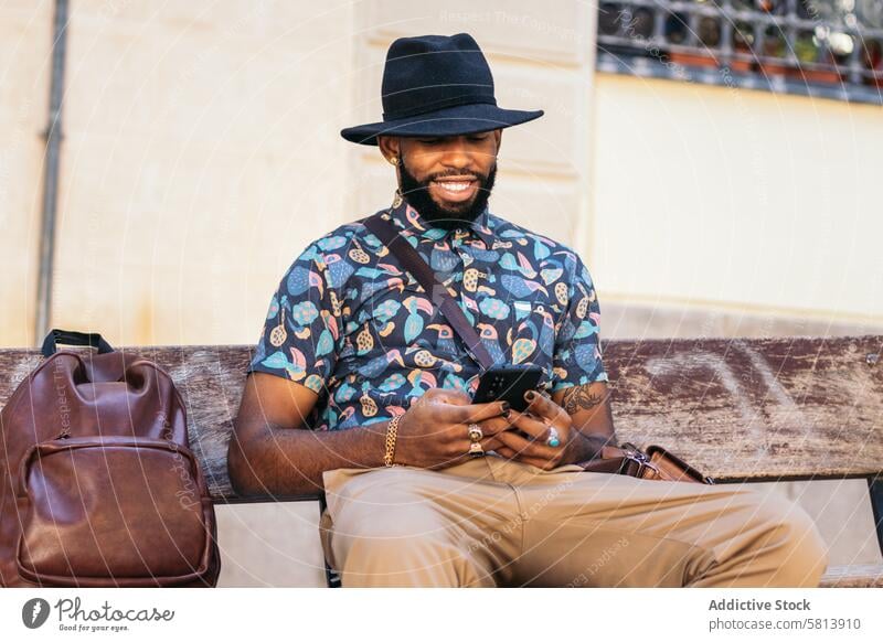 Stylish black man in the city street using smartphone technology lifestyle young urban mobile male person cellphone stylish guy outside people casual looking