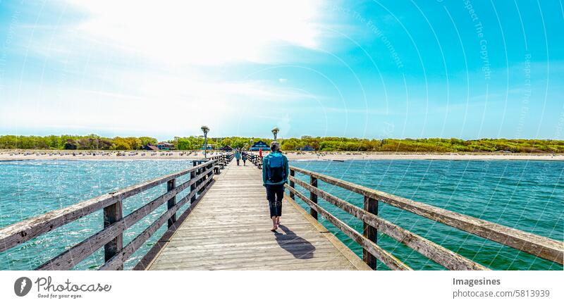 Man with backpack walking across the pier Graal Müritz, Baltic Sea, Germany. View of the land from the bridge backpacker Sea bridge Ocean graal müritz Bridge