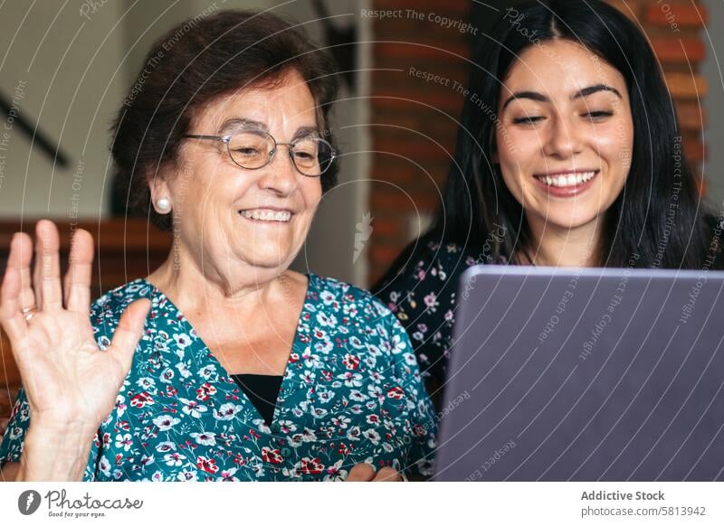 Grandmother and granddaughter making video call with laptop at home internet family computer online senior old grandmother technology girl happy woman together