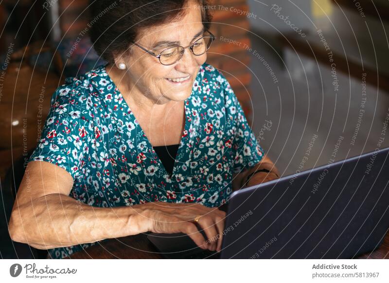 Senior woman with glasses using a laptop at home senior technology computer mature happy female internet person people sitting lifestyle adult smiling elderly