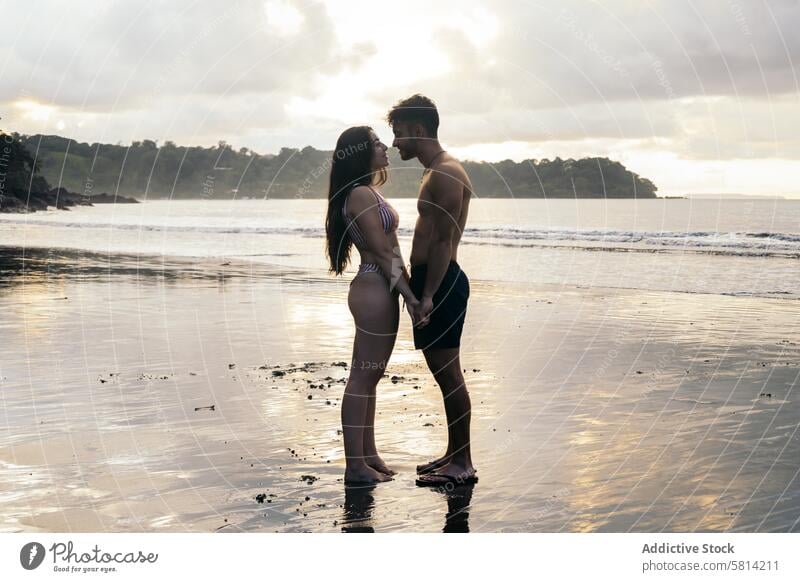 Young couple standing on the beach at sunset love together man romance happy people young two ocean romantic female vacation lovers relationship kiss sea woman