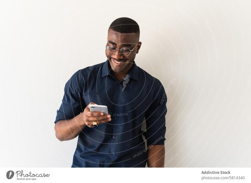 Happy black guy with phone and laptop near white wall man smartphone well dressed modern eyeglasses studio shot netbook african american male adult shirt