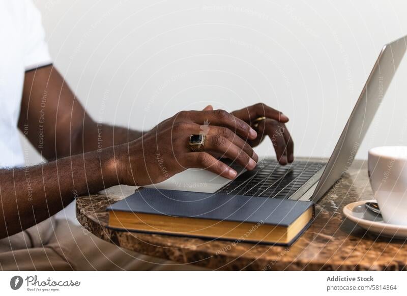 African American man using laptop at table in cafe cup drink modern african american black male adult online computer lifestyle surfing t shirt light bright