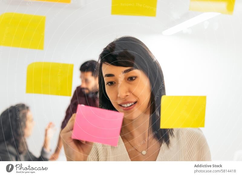 Asian woman writing on sticky notes brainstorming ideas from company meeting in coworking space ethnicity asian diversity office business productivity