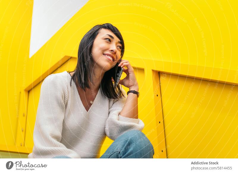 Smiling Asian woman talking on the phone in a coworking Phone call Coworking space Shared office Remote work Professional Entrepreneur Startup Freelance