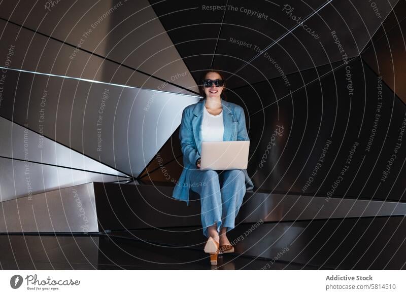 Woman in sunglasses browsing laptop in studio woman futuristic 3d modern design online internet gadget using device elegant female wall connection style