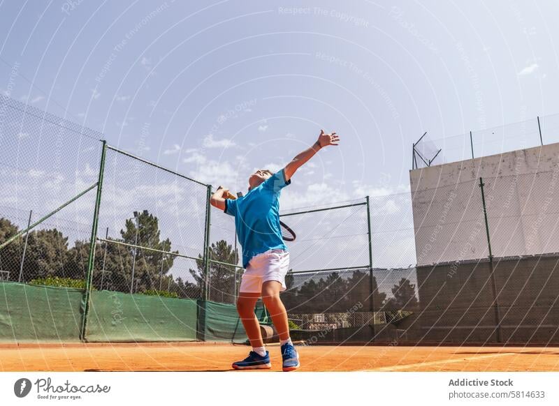 Little boy playing tennis on a dirt court making a serve activity sport game racket child person player kid athlete training lifestyle childhood healthy