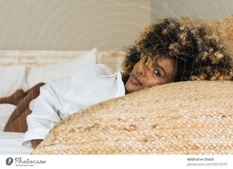 Thoughtful black woman lying on bed in bedroom enjoy rest positive comfort relax morning pleasure female happy optimist delight cheerful toothy smile home glad