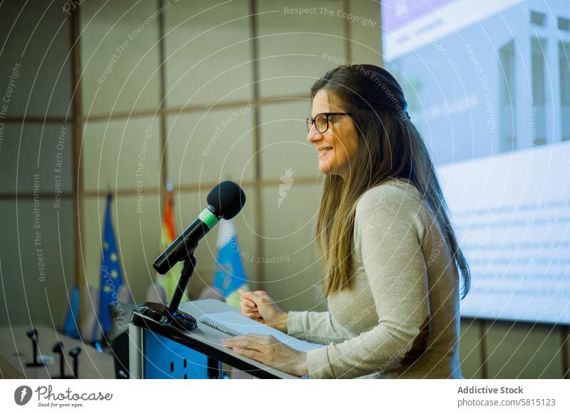 Smiling woman giving lecture in university tutor speaker seminar presentation mic teacher microphone female lecturer study auditorium meeting lady conference