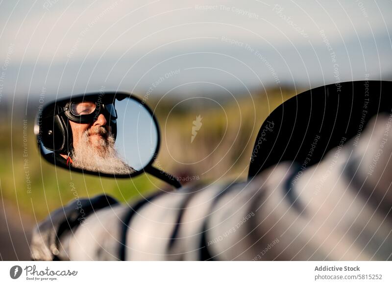 Senior biker reflected in motorcycle mirror senior male motorcyclist reflection side mirror enjoyment freedom ride elderly adult transport leisure lifestyle