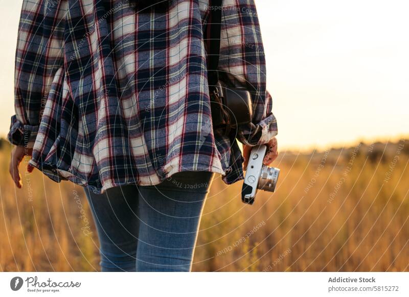 Unrecognizable woman taking photos with analog camera in the countryside lifestyle young girl photography vintage retro travel sunset hipster photographer