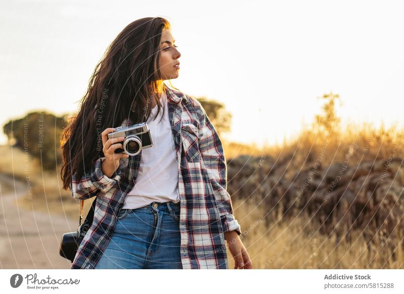 Young woman taking photos with analog camera in the field at sunset lifestyle young girl photography vintage retro travel hipster photographer beautiful people