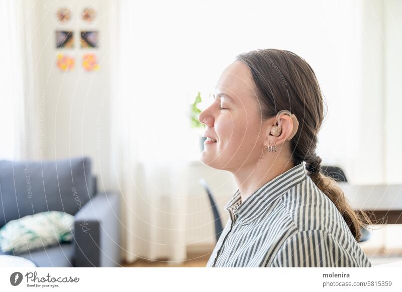 Portrait of woman with hearing aid person deaf health device adult female disability assistance 30s white smiling portrait shirt home