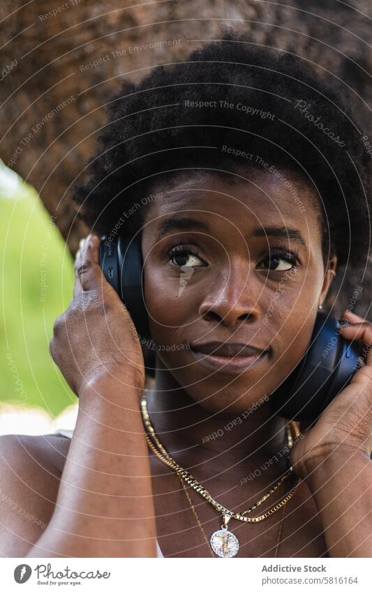 Black woman listening to music in headphones happy song using wireless tune enjoy female device afro hair glad fun audio optimist smile delight lady