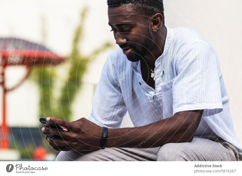 Black man using smartphone in city street busy freelance project male ethnic black african american mobile phone communicate cellphone gadget device sit style