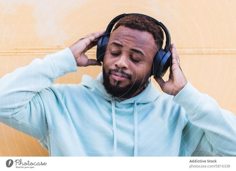 Optimistic black hipster listening to music with headphones man happy enjoy cheerful beard wireless adult african american ethnic male optimist casual device