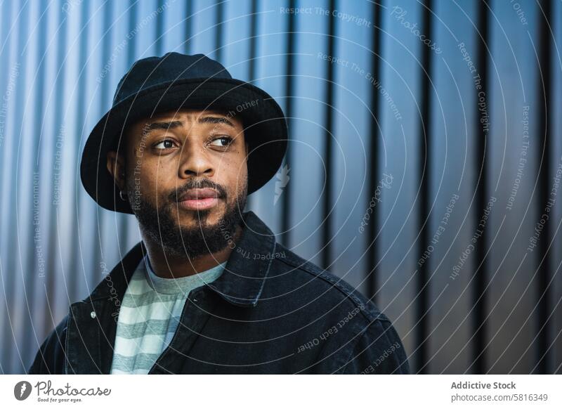 Smiling black hipster man in hat looking away trendy beard male african american ethnic outfit style lifestyle delight urban cool fashion accessory friendly