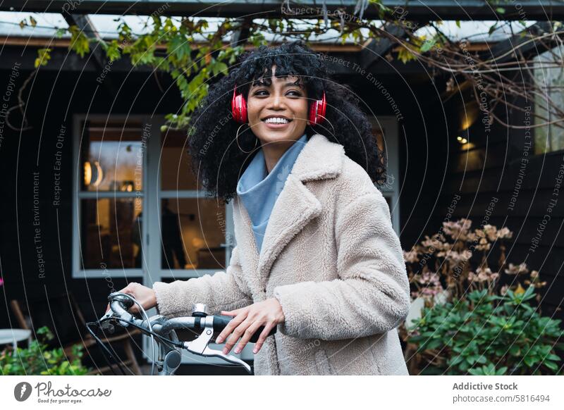 Cheerful black woman in headphones with bicycle using music listen bike chill relax city female african american woman street smile walk stroll positive rest