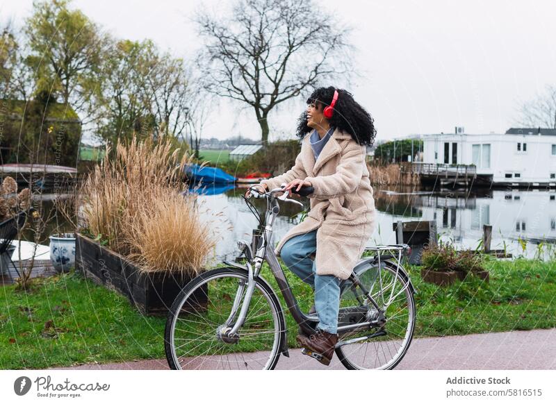 Excited black woman in headphones riding bicycle using music listen ride bike chill city female portrait african american woman relax street smile positive rest