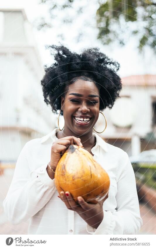 Latin American woman having fun in the city drinking coconuts happy young summer female outdoors people leisure lifestyle joyful spring enjoyment hair curly