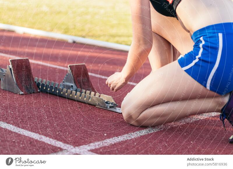 A female athlete getting ready to run on an athletics track. fitness lifestyle sport runner workout exercise training healthy woman active person outdoors young