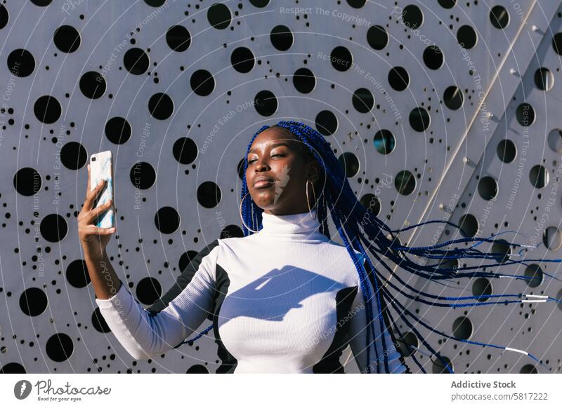 Serious black woman taking selfie on street blue hair braid hairstyle serious trendy color smartphone female ethnic african american environment photo urban