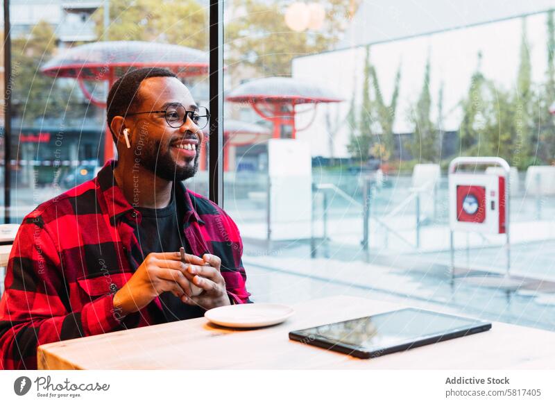 Smiling black man with cup of coffee in cafe earphones using hot drink coffee break music rest relax male african american beverage smile listen enjoy weekend